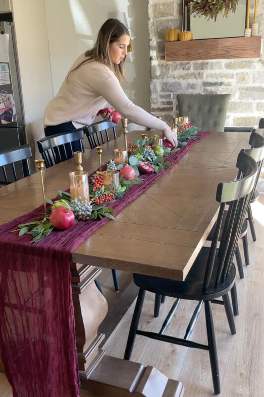 Tucking halved pomegranates, berries, and faux artichokes into the greenery